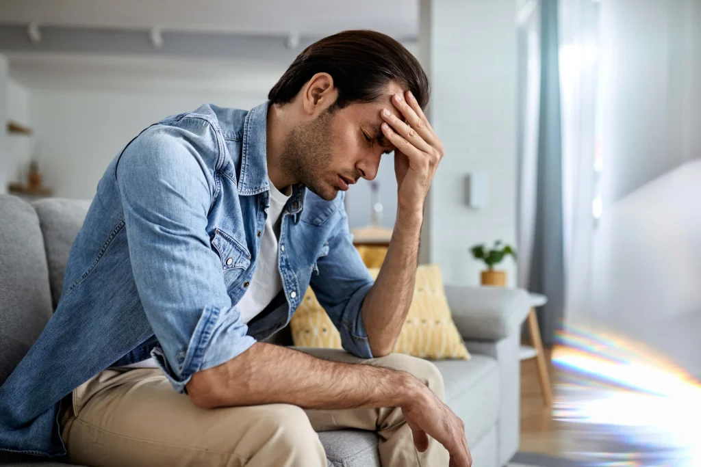 young man having headache holding his head pain home min scaled 1
