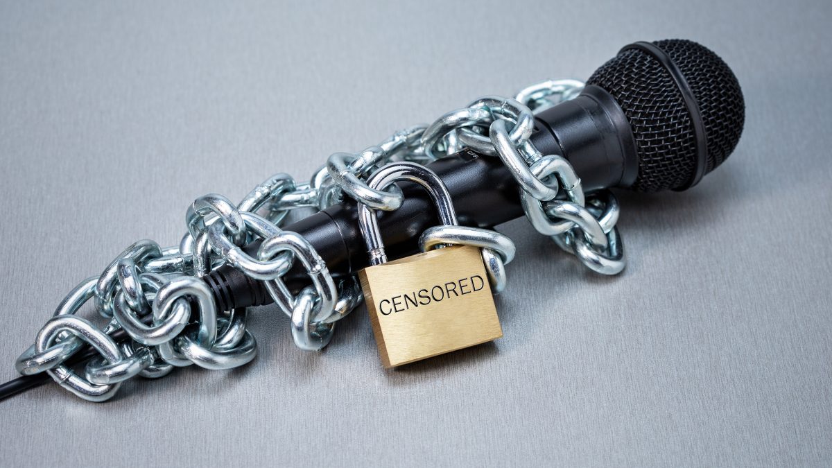 censored right speak microphone entangled with iron chain lock desk 1200x675 1