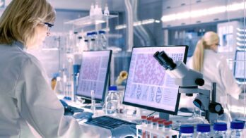 Senior Female Scientist Works with High Tech Equipment in a Modern Laboratory. Her Colleagues are Working Beside Her.