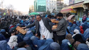 mehr del khan rahmati, in charge of the bakery, distributes bread among the needy in front of the bakery in kabul
