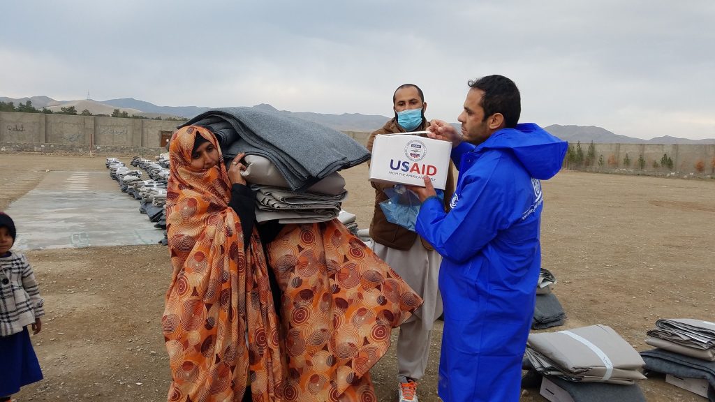 a female headed household receiving assistance IOM staff helping the beneficiary in carrying the package Herat 21 Nov 2018 50