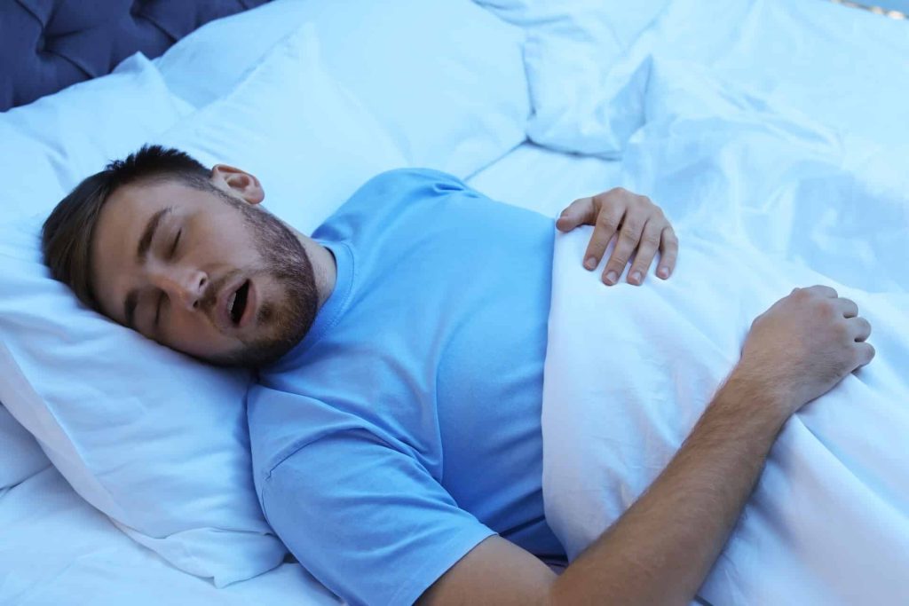 a young man snoring while sleeping in bed